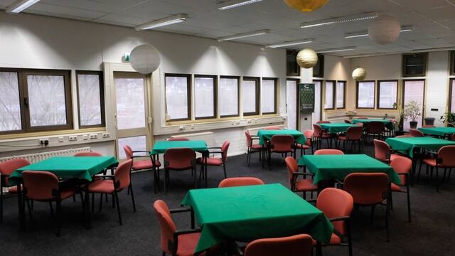 Lege speelzaal met groene bridgetafels en stoelen