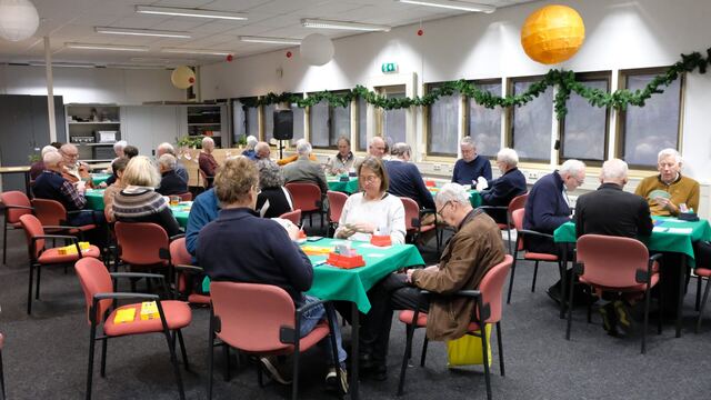 Spelers aan groene tafels in een zaal met kerstversiering