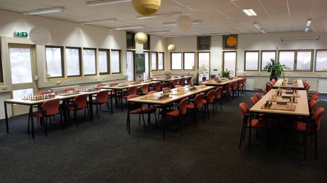 Lange tafels met opgestelde schaakborden in de grote zaal
